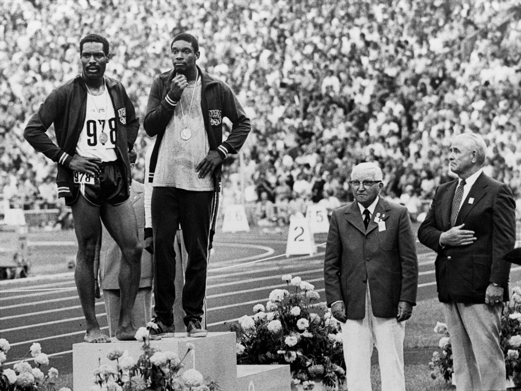 Two Olympic officials stand at attention, right, as U.S. runners Wayne Collett (978) and Vince Matthews stand at ease on the top level of the victory stand Sept. 7, 1972 at Olympic Stadium in Munich.  The crowd booed the two after Collett, who placed second in the 400-meter dash, joined first-place Matthews on the top level.  The two then stood at ease and sideways to the flag as the National Anthem was played in a protest of U.S. civil rights policies back home..  The International Olympic Committee banned the two from further competition although Matthews said later that no disrespect was intended. (AP Photo)