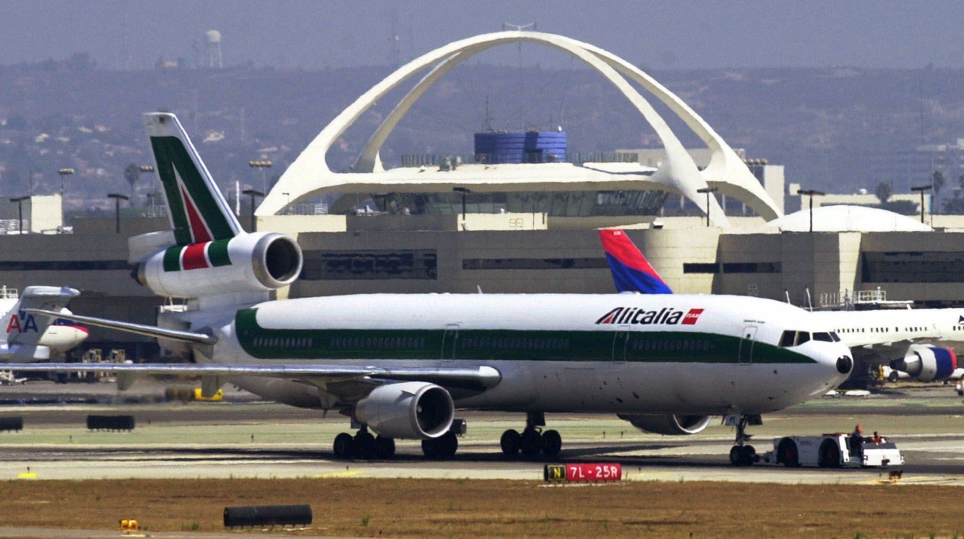An Alitalia MD-11 jetliner, the first plane to land at Los Angeles International Airport after air operations resumed Thursday, Sept. 13, 2001, is towed past the airport theme building after unloading passengers at a terminal.  All U.S. air travel was shut down Tuesday after terrorist attacks in New York and Washington.  LAX was the destination airport of three of the four flights that were lost in the terrorist attacks.  (AP Photo/Reed Saxon)