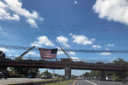 A flag is seen above US 50 at Church Road in Bowie, Maryland, as Sen. John McCain's funeral procession makes its way to the US Naval Academy in Annapolis, Maryland. (WTOP/Valerie Bonk)