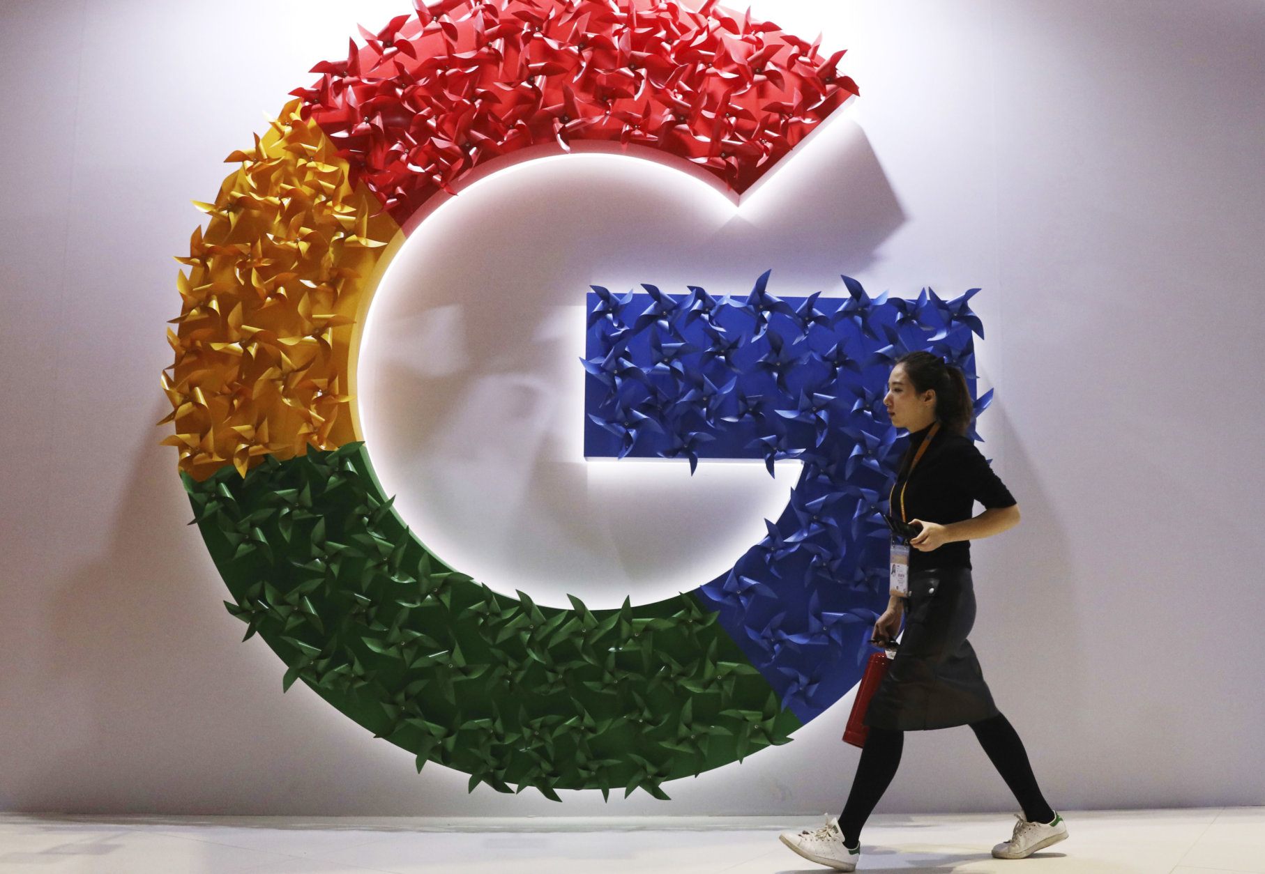 FILE - In this Monday, Nov. 5, 2018 file photo, a woman walks past the logo for Google at the China International Import Expo in Shanghai. The European Union’s executive Commission has slapped Google with multibillion dollar fines for repeatedly abusing its market dominance to stifle competition, and demanded that online companies explain more clearly to users what happens to their personal data. (AP Photo/Ng Han Guan, FILE)