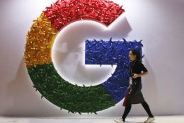 FILE - In this Monday, Nov. 5, 2018 file photo, a woman walks past the logo for Google at the China International Import Expo in Shanghai. The European Union’s executive Commission has slapped Google with multibillion dollar fines for repeatedly abusing its market dominance to stifle competition, and demanded that online companies explain more clearly to users what happens to their personal data. (AP Photo/Ng Han Guan, FILE)