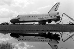 The space shuttle Discovery is reflected in a canal at the Kennedy Space Center as it is towed to the orbital processing facility on Nov. 16, 1984 after successfully completing Mission 51-A with a crew of five.  (AP Photo/Phil Sandlin)