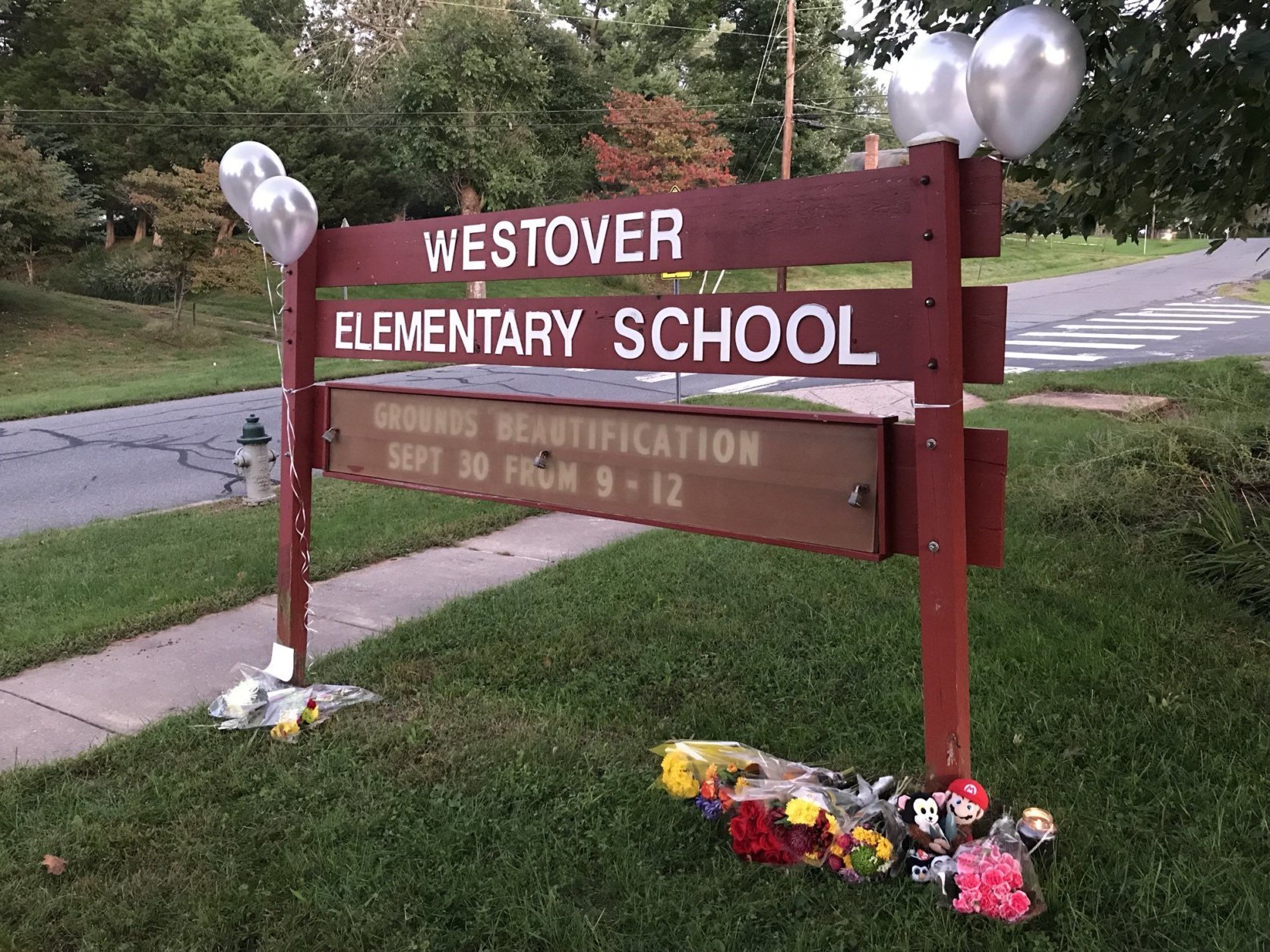 Before the vigil, some people placed flowers and other mementos under the school's wooden sign. (WTOP/Michelle Basch)