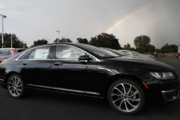 FILE- In this July 8, 2018, file photo a rainbow illuminates the sky as 2018 MKZ sedans MKX as they sit outside a Lincoln dealership in Englewood, Colo. On Wednesday, Aug 15, the Commerce Department releases U.S. retail sales data for July. (AP Photo/David Zalubowski, File)