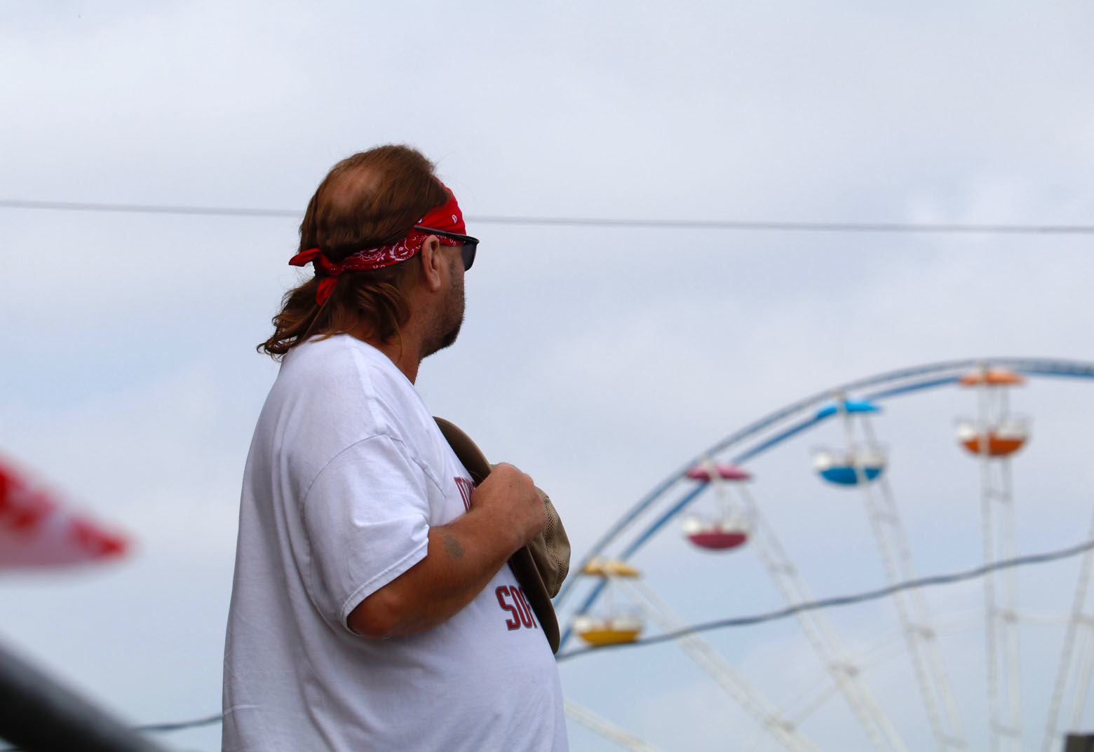 Before the harness racing at the Great Frederick Fair, a spectator stands for the playing of the national anthem. (WTOP/Kate Ryan)