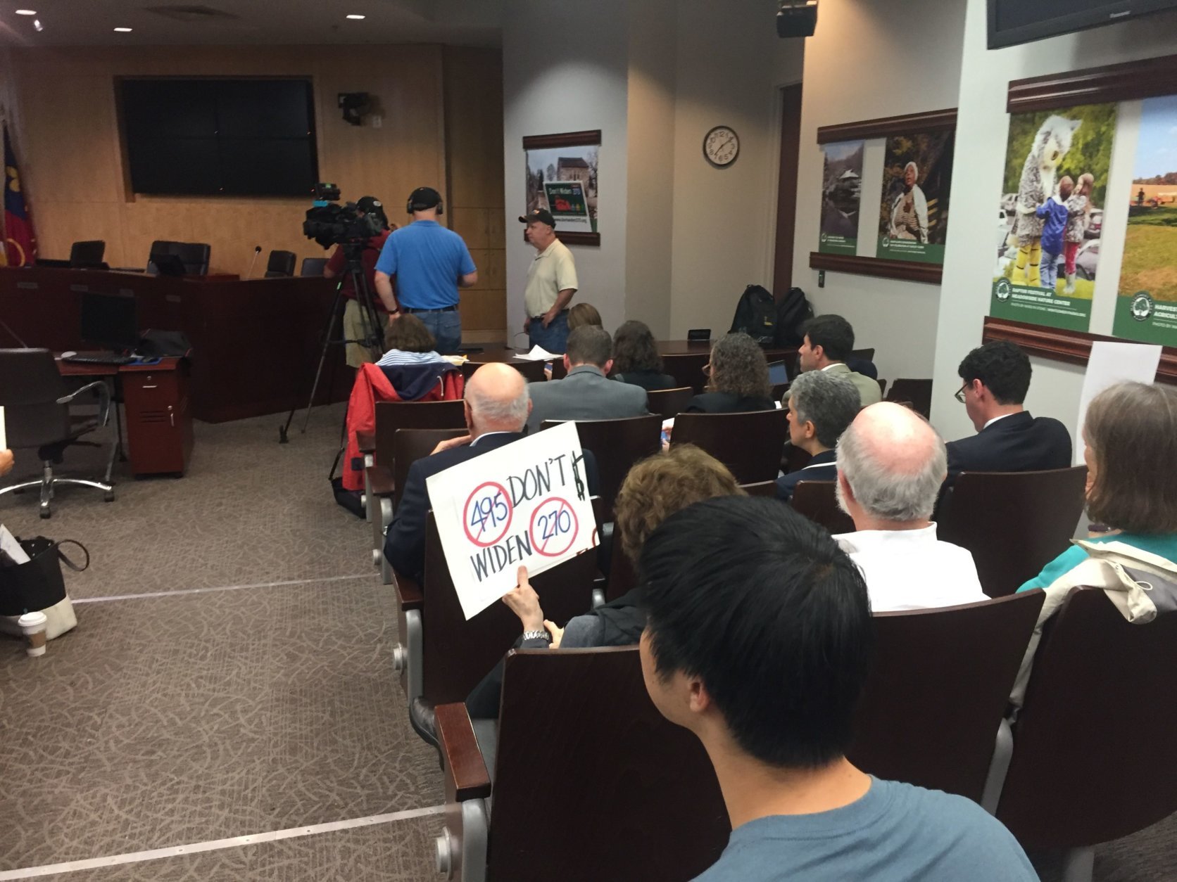 Residents holding signs which read, “Don’t widen 270 & 495” attended a public meeting Thursday, Oct. 11, 2018. (WTOP/Mike Murillo)