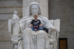 Jessica Campbell-Swanson, an activist from Denver, sits in the lap of a sculpture known as the Statue of Contemplation of Justice on the steps of the Supreme Court Building where she and others protested the confirmation of Brett Kavanaugh as the high court's newest justice, in Washington, Saturday, Oct. 6, 2018. Kavanaugh took the oath inside the building after the bitterly polarized U.S. Senate narrowly confirmed him, delivering an election-season triumph to President Donald Trump that could swing the court rightward for a generation. (AP Photo/J. Scott Applewhite)