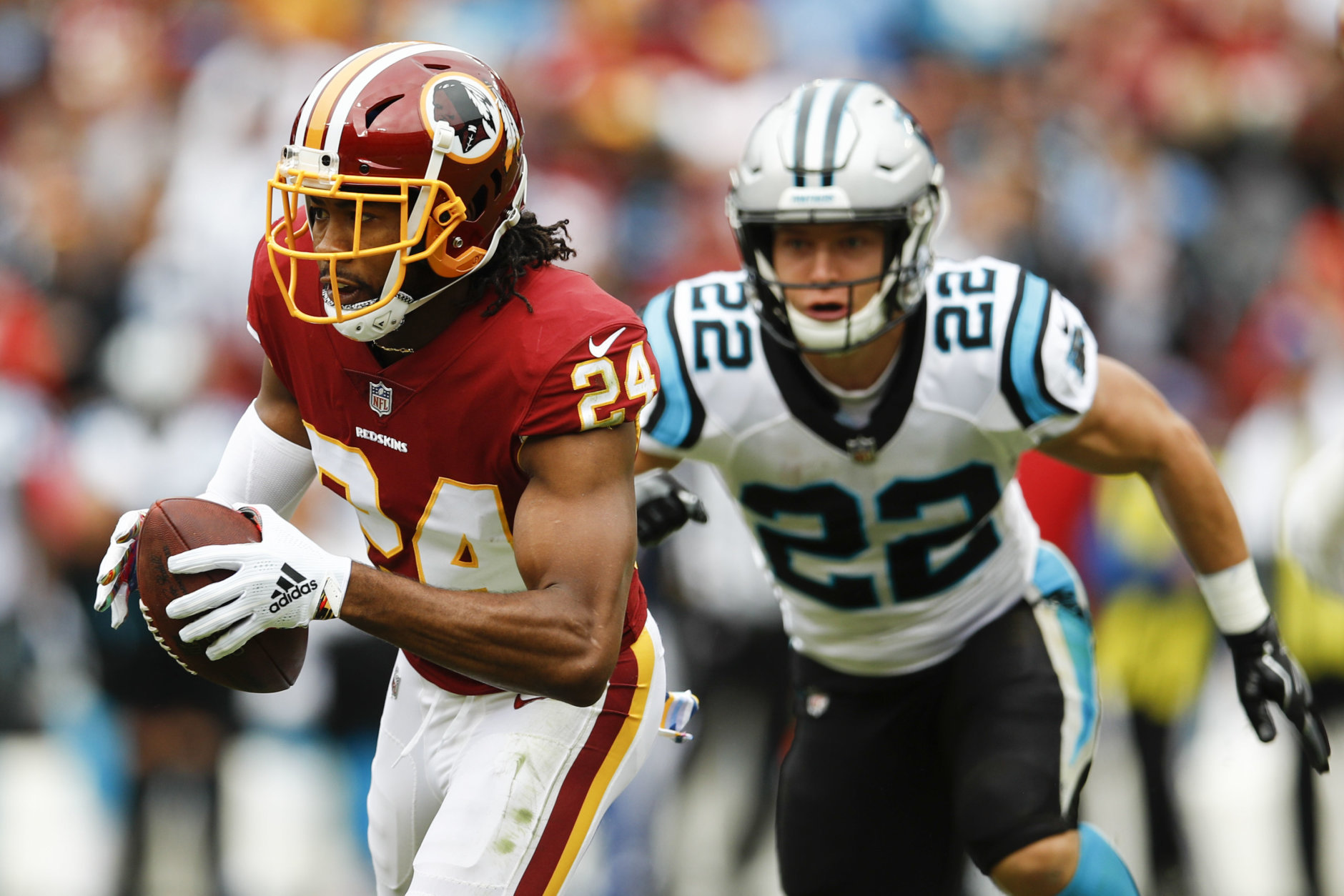 Washington Redskins cornerback Josh Norman (24) carries the ball after pulling in an interception as Carolina Panthers running back Christian McCaffrey (22) pursues him during the first half of an NFL football game, Sunday, Oct. 14, 2018, in Landover, Md. (AP Photo/Patrick Semansky)