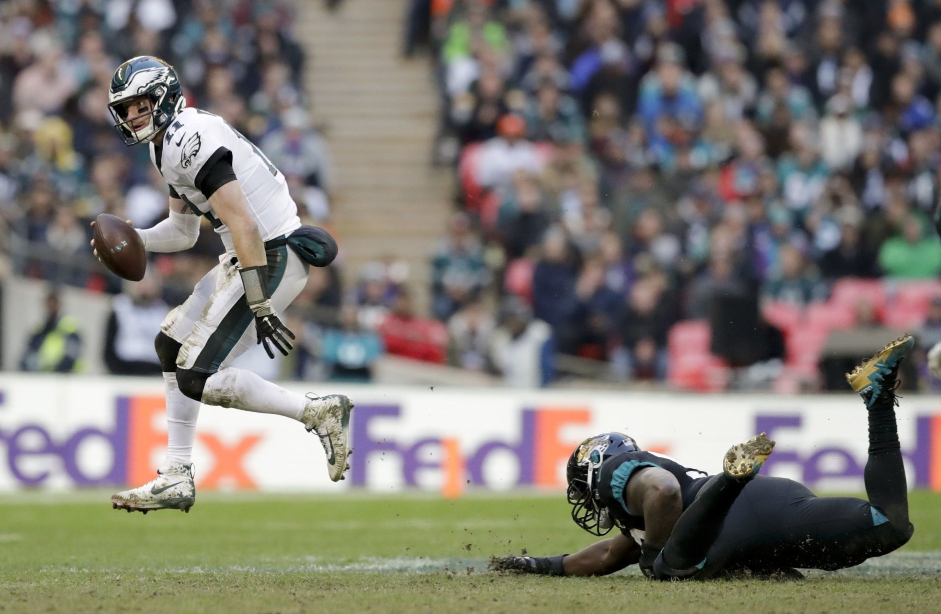 Philadelphia Eagles quarterback Carson Wentz (11), left, skips out of a tackle during the second half of an NFL football game against Jacksonville Jaguars at Wembley stadium in London, Sunday, Oct. 28, 2018. (AP Photo/Matt Dunham)