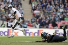 Philadelphia Eagles quarterback Carson Wentz (11), left, skips out of a tackle during the second half of an NFL football game against Jacksonville Jaguars at Wembley stadium in London, Sunday, Oct. 28, 2018. (AP Photo/Matt Dunham)