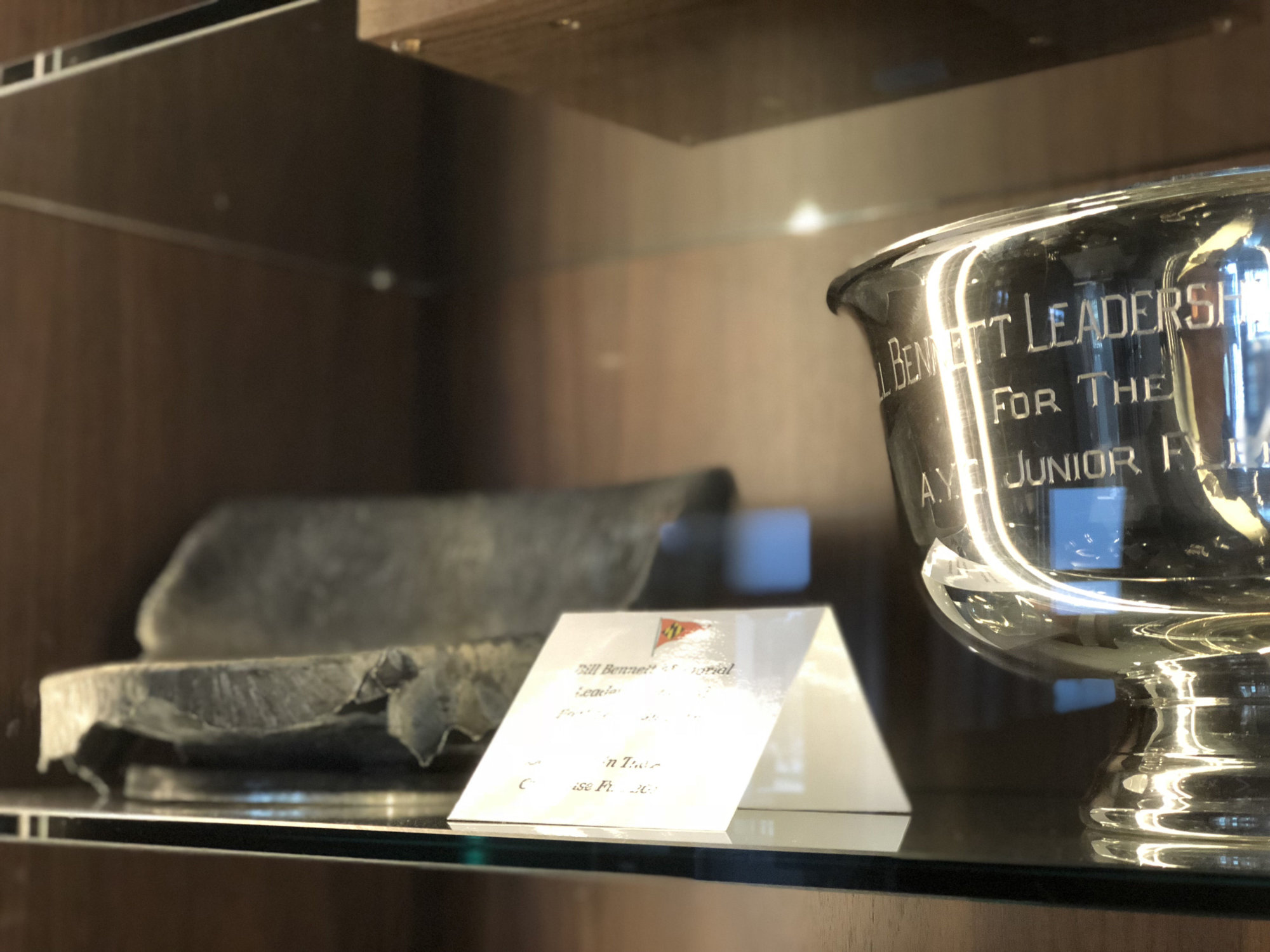 On the left is what’s left of the original Bill Bennett Leadership Award, presented to the Junior Fleet. It was destroyed in the 2015 Annapolis Yacht Club fire. You can see how it was melted down in the heat. On the right is the new version. (WTOP/Kate Ryan)