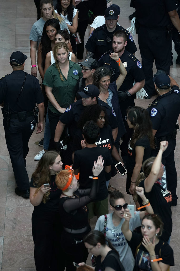 WASHINGTON, DC - OCTOBER 04:  Comedian Amy Schumer, in green, is led away after she was arrested with other demonstrators during a protest against the confirmation of Supreme Court nominee Judge Brett Kavanaugh October 4, 2018 at the Hart Senate Office Building on Capitol Hill in Washington, DC. Senators had an opportunity to review a new FBI background investigation into accusations of sexual assault against Kavanaugh and Republican leaders are moving to have a vote on his confirmation this weekend. (Photo by Alex Wong/Getty Images)