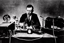 Italian physicist Guglielmo Marconi, who claimed he invented radio, reads signals on a tape recorder, left, with a 10-inch spark coil used for ship-to-shore radio tests in this 1901 photo.  (AP Photo)