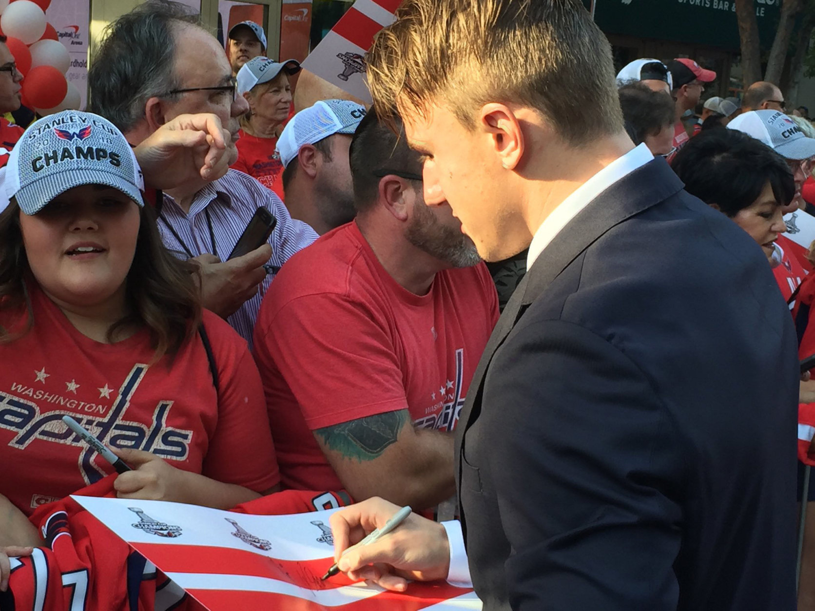 The Capitals' Jacob Vrana signs an autograph as the Caps arrive at the 2018-2019 season opener. (WTOP/Jonathan Warner)