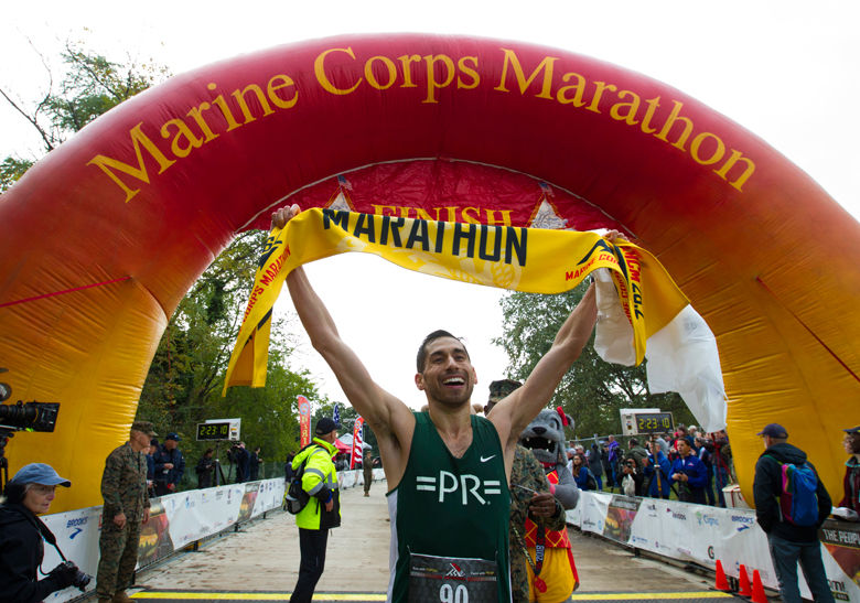 Jeffery Stein holds the banner as he crosses the finish line to win the Marine Corps Marathon men's division. (AP Photo/Jose Luis Magana)