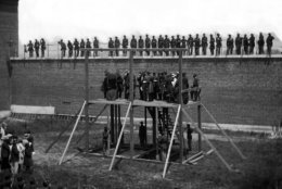 The four condemned Lincoln assassination conspirators (Mary Surratt, Lewis Payne, David E. Herold, George A. Atzerodt), with officers and others on the scaffold, with guards on the wall, in 1865. (Courtesy Library of Congress)