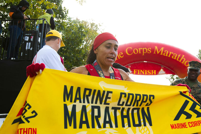Jenny Mendez of Costa Rica holds the marathon banner after she finished in first place in the women's division of the 43rd Marine Corps Marathon, Sunday, Oct. 28, 2018, in Arlington, Va. (AP Photo/Jose Luis Magana)
