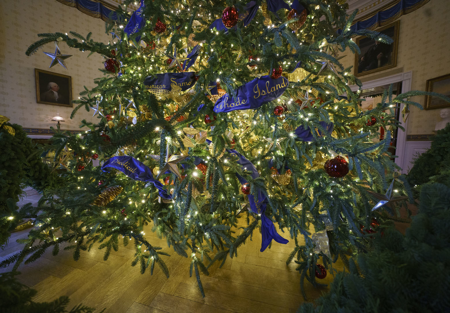 The base of the official White House Christmas tree is seen in the Blue Room during the 2018 Christmas Press Preview at the White House in Washington, Monday, Nov. 26, 2018. The tree measures 18 feet tall and is dressed in over 500 feet of blue velvet ribbon embroidered in gold with each State and territory. Christmas has arrived at the White House. First lady Melania Trump unveiled the 2018 White House holiday decor on Monday. She designed the decor, which features a theme of "American Treasures." (AP Photo/Carolyn Kaster)