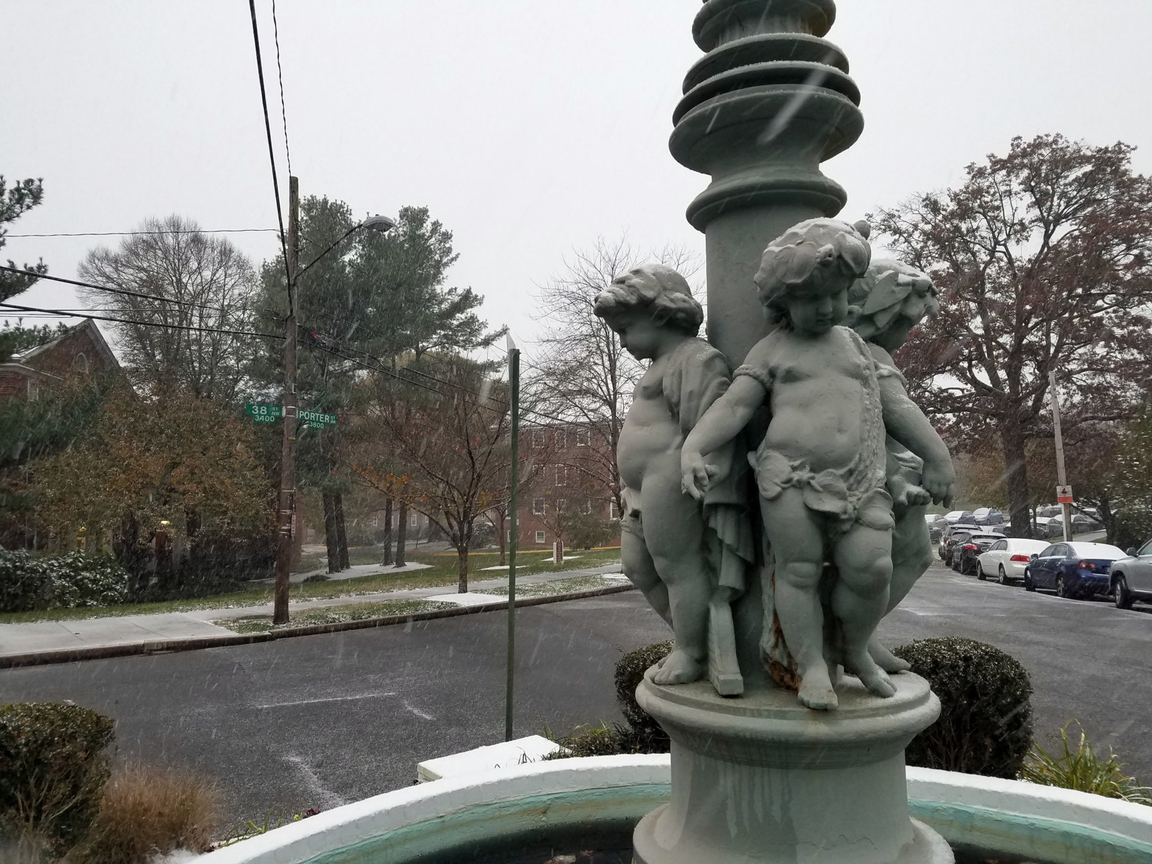 Snow falls around a statue in Northwest D.C. (WTOP/Will Vitka)