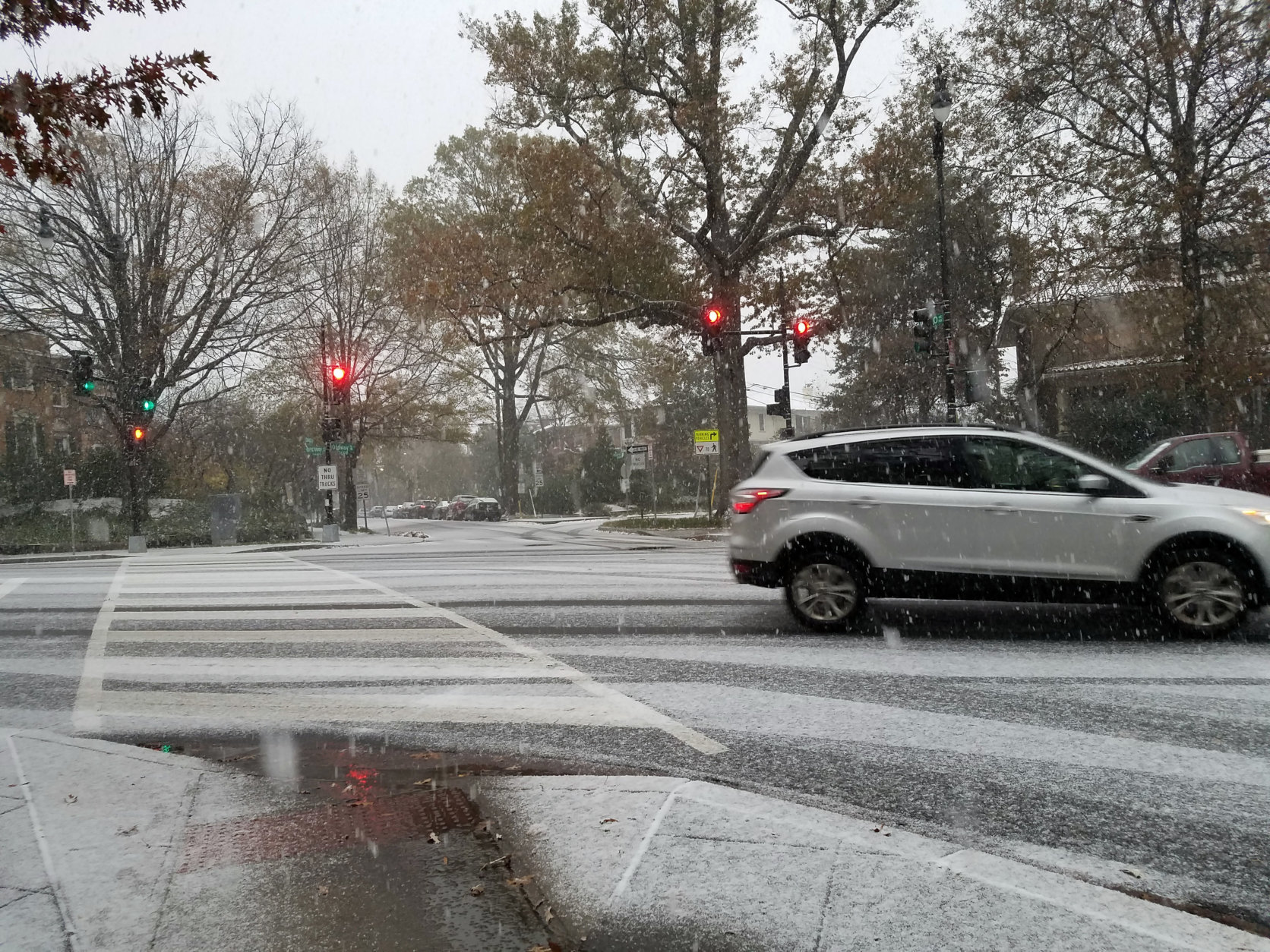 Cars make their way through Northwest D.C. as snow falls Thursday. (WTOP/Will Vitka)