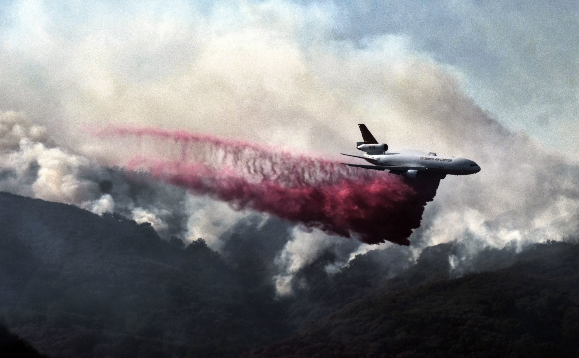 A firefighting DC-10 makes a fire retardant drop over a wildfire in the mountains near Malibu Canyon Road in Malibu, Calif. on Sunday, Nov. 11, 2018. Strong Santa Ana winds have returned to Southern California, fanning a huge wildfire that has scorched a string of communities west of Los Angeles. A one-day lull in the dry, northeasterly winds ended Sunday morning and authorities warn that the gusts will continue through Tuesday. (AP Photo/Richard Vogel)