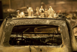 Following the Camp Fire, figurines rest atop a scorched car on Pearson Road, Monday, Nov. 12, 2018, in Paradise, Calif. (AP Photo/Noah Berger)
