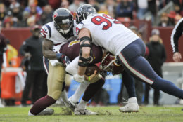 Washington Redskins quarterback Alex Smith (11) ankle is injured as he is sacked by Houston Texans defensive end J.J. Watt (99) and Houston Texans strong safety Kareem Jackson (25) during the second half of an NFL football game, Sunday, Nov. 18, 2018 in Landover, Md. (AP Photo/Mark Tenally)