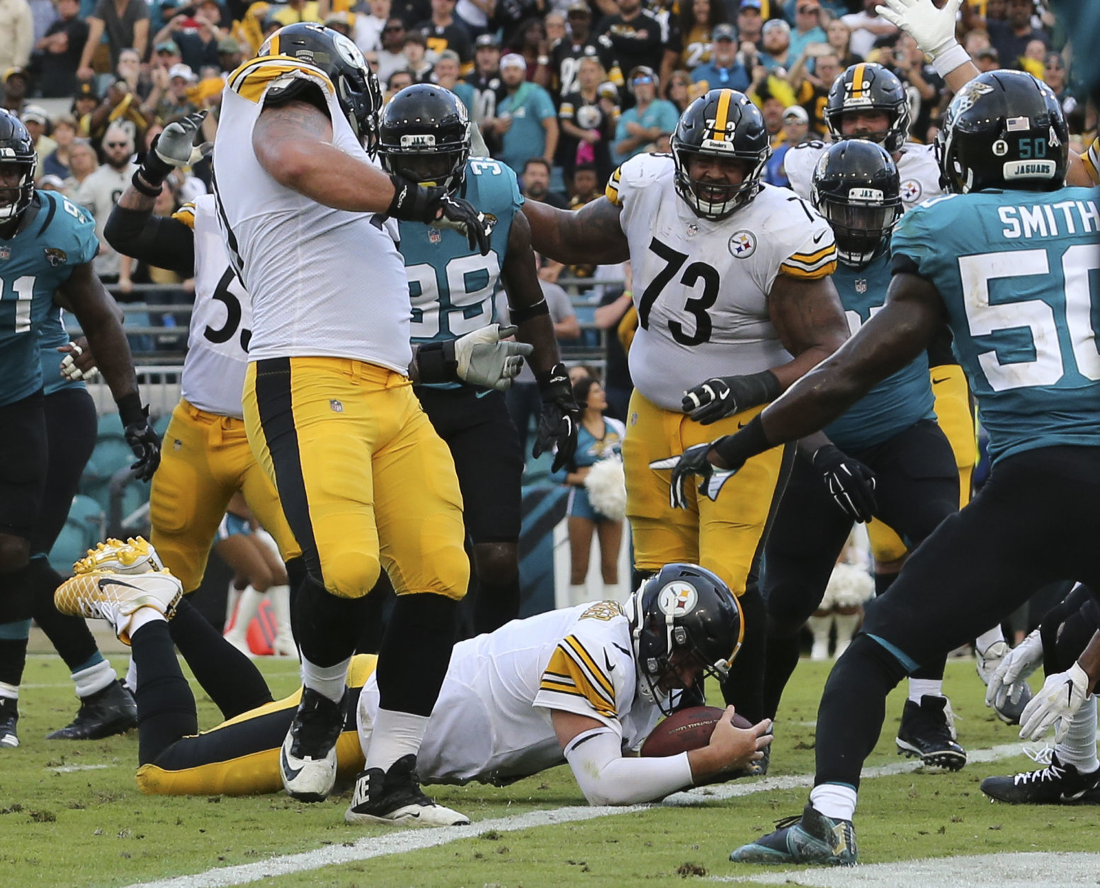 Pittsburgh Steelers quarterback Ben Roethlisberger dives over the goal line for the go ahead touchdown in front of Jacksonville Jaguars outside linebacker Telvin Smith, right, during the final seconds of an NFL football game, Sunday, Nov. 18, 2018, in Jacksonville, Fla. (AP Photo/Gary McCullough)