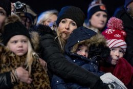 A woman and children in the front row huddle together to stay warm during the National Christmas Tree lighting ceremony at the Ellipse near the White House in Washington, Wednesday, Nov. 28, 2018. (AP Photo/Andrew Harnik)