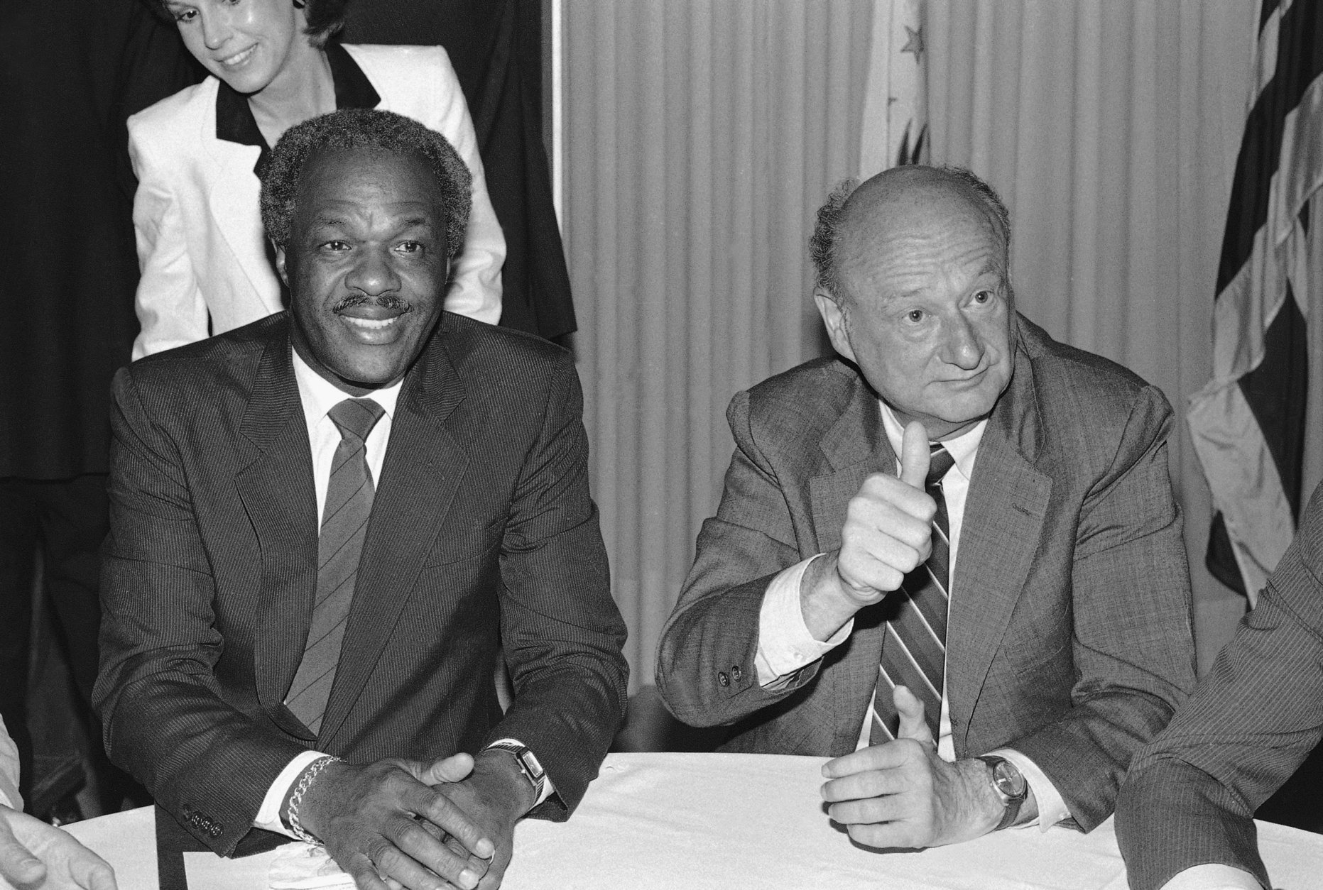 New York Mayor Edward Koch, right, gives the thumbs-up sign as he sits with Washington Mayor Marion Barry, Monday, July 1, 1985 at the National Press Club in Washington. The men were at the Press Club for a gala salute to the National Press Club/Washington press Club merger party. (AP Photo/Ken Heinen)
