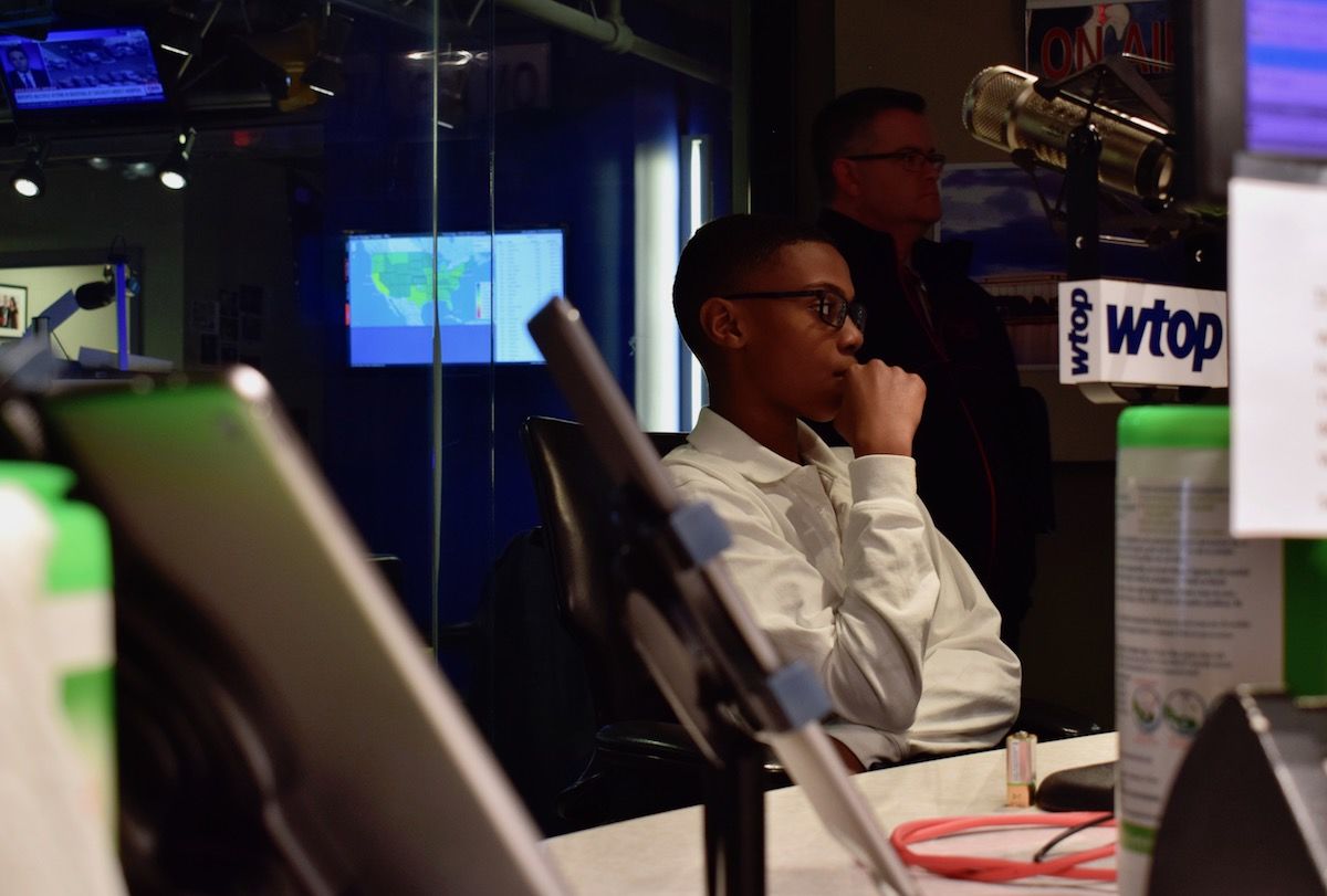 Sylvestre watches WTOP afternoon anchor Shawn Anderson deliver breaking news. (WTOP/Teta Alim)