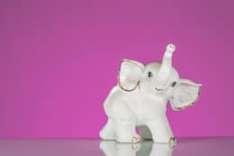 Closeup of white elephant made of porcelain, pink background