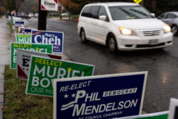 Signs for local candidates compete for space on the sidewalk as voters arrive at the Washington Hebrew Congregation in Northwest D.C. (WTOP/Alejandro Alvarez)