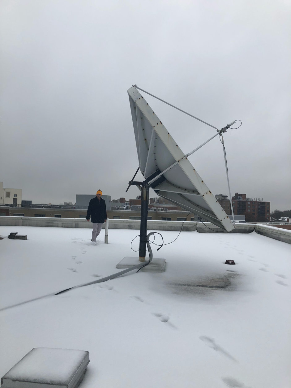 WTOP's Chris Cichon hits the roof at WTOP to clean off the satellite dish. (WTOP/Nahal Amouzadeh)