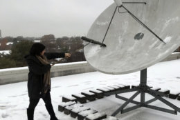 WTOP's Alicia Abelson braves the nasty weather to help clean the station's satellite dish. (WTOP/Chris Cichon)