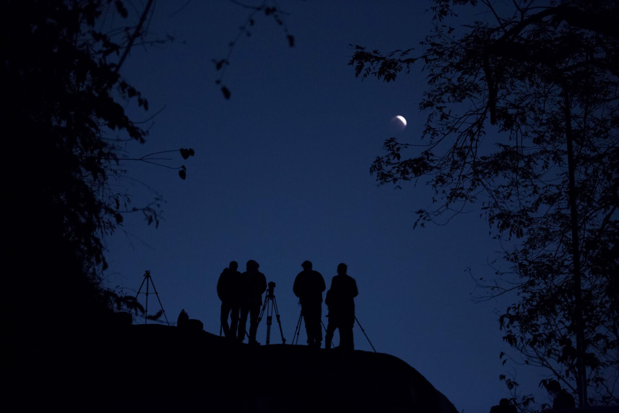 People use telescopes to observe the lunar eclipse in Gauhati, India, Wednesday, Jan. 31, 2018. The moon is putting on a rare cosmic show. It's the first time in 35 years a blue moon has synced up with a supermoon and a total lunar eclipse. NASA is calling it a lunar trifecta: the first super blue blood moon since 1982. That combination won't happen again until 2037. (AP Photo/Anupam Nath)