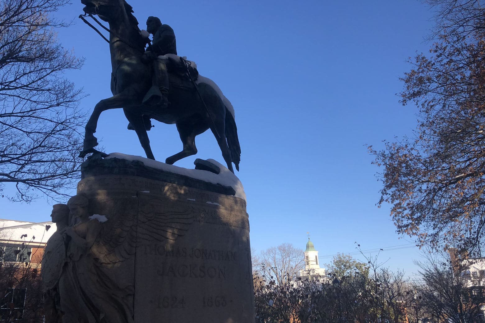 The statue of Stonewall Jackson in Charlottesville is seen Dec. 11, 2018. The white belltower of Charlottesville Circuit Court, where a jury is deliberating the sentence of James Alex Fields Jr., is seen in the background. (WTOP/Max Smith)