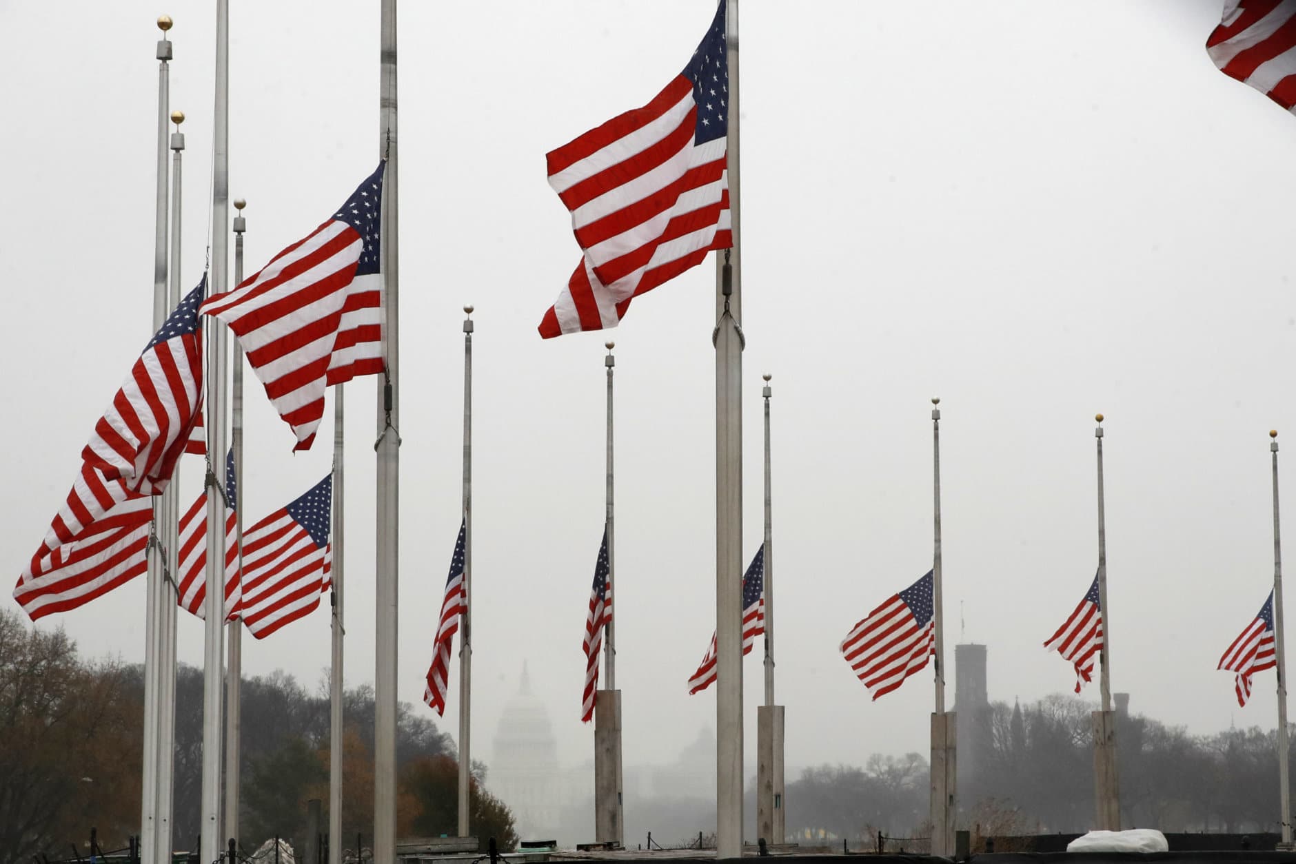With a misty U.S. Capitol in the distance, the American flags surrounding the Washington Monument fly at half-staff, Saturday, Dec. 1, 2018, in Washington, after President Donald Trump directed that American flags be flown at half-staff for 30 days to honor the memory of former President George H.W. Bush. (AP Photo/Jacquelyn Martin)