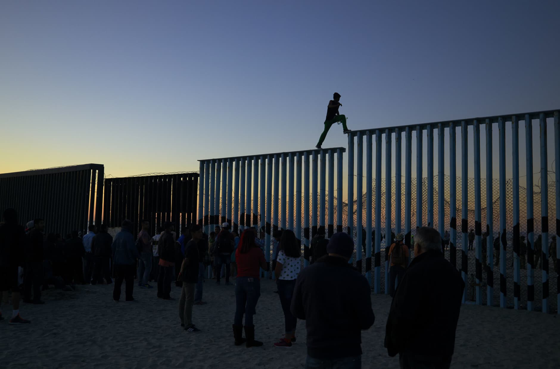 A man from Honduras walks along the top of the border structure separating Mexico and the United States on Nov. 14, 2018, in Tijuana, Mexico. (AP Photo/Gregory Bull)