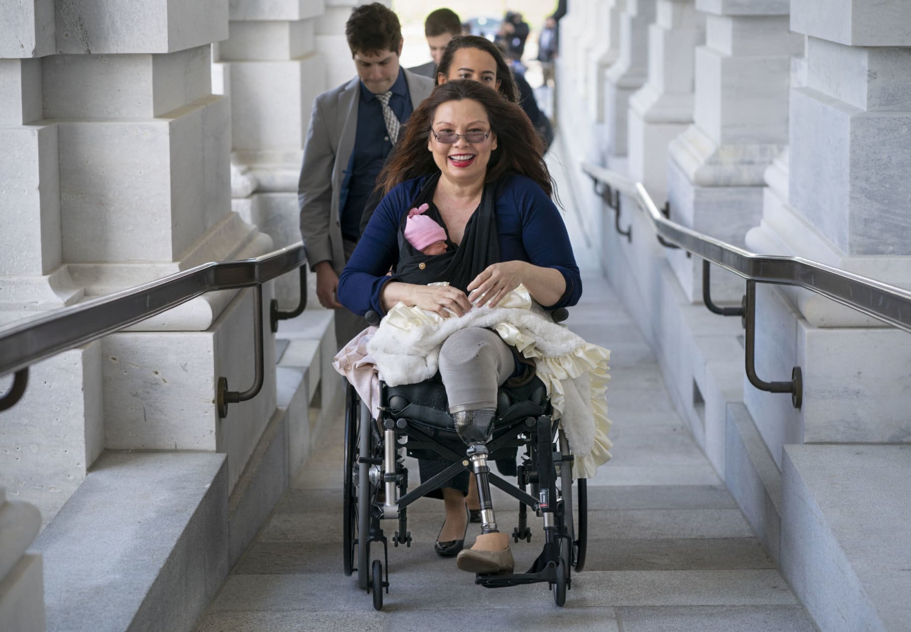 Sen. Tammy Duckworth, D-Ill., arrives at the Capitol for a close vote with her new daughter, Maile, bundled against the wind, in Washington on April 19, 2018. In an historic change in Senate rules, the lawmakers decided to allow babies of members on the floor during votes. (AP Photo/J. Scott Applewhite)