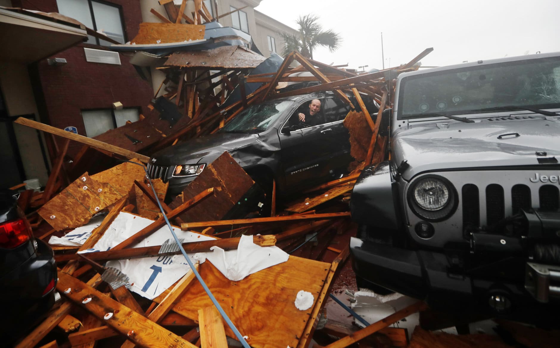 A storm chaser climbs into his vehicle to retrieve equipment after a hotel canopy collapsed, as the eye of Hurricane Michael passes over Panama City Beach, Fla., on Oct. 10, 2018. (AP Photo/Gerald Herbert)