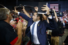 A volunteer member of the advance team for President Donald Trump blocks a camera as a photojournalist attempts to take a photo of a protester during a campaign rally in Evansville, Ind., on Aug. 30, 2018. (AP Photo/Evan Vucci)