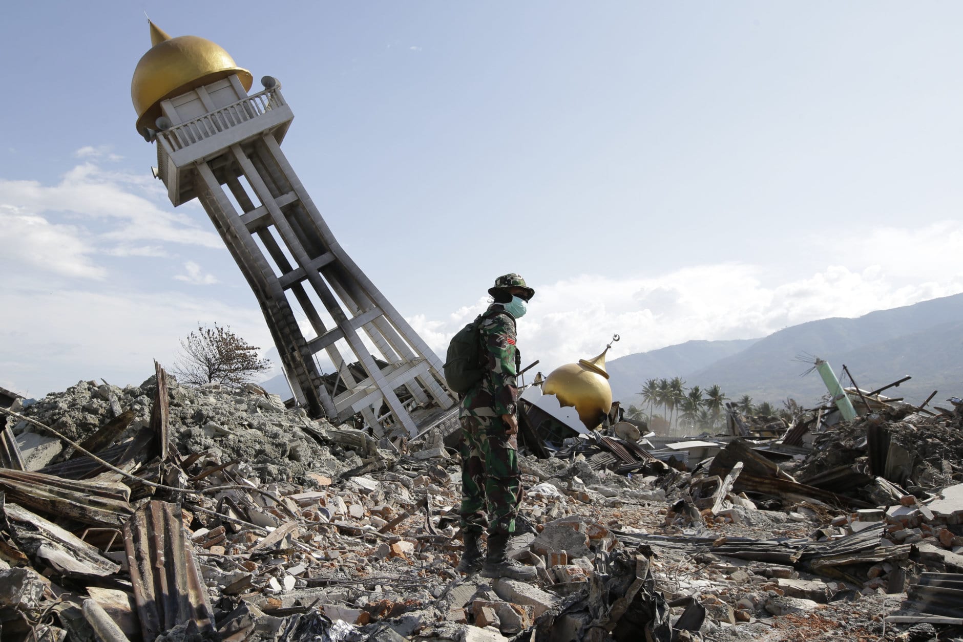An Indonesian trooper stands beside a toppled mosque as recovery efforts continue at the earthquake-hit Balaroa neighborhood in Palu, Central Sulawesi, Indonesia, on Oct. 6, 2018. (AP Photo/Aaron Favila)