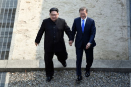 North Korean leader Kim Jong Un, left, and South Korean President Moon Jae-in cross the military demarcation line at the border village of Panmunjom in Demilitarized Zone on April 27, 2018. (Korea Summit Press Pool via AP)
