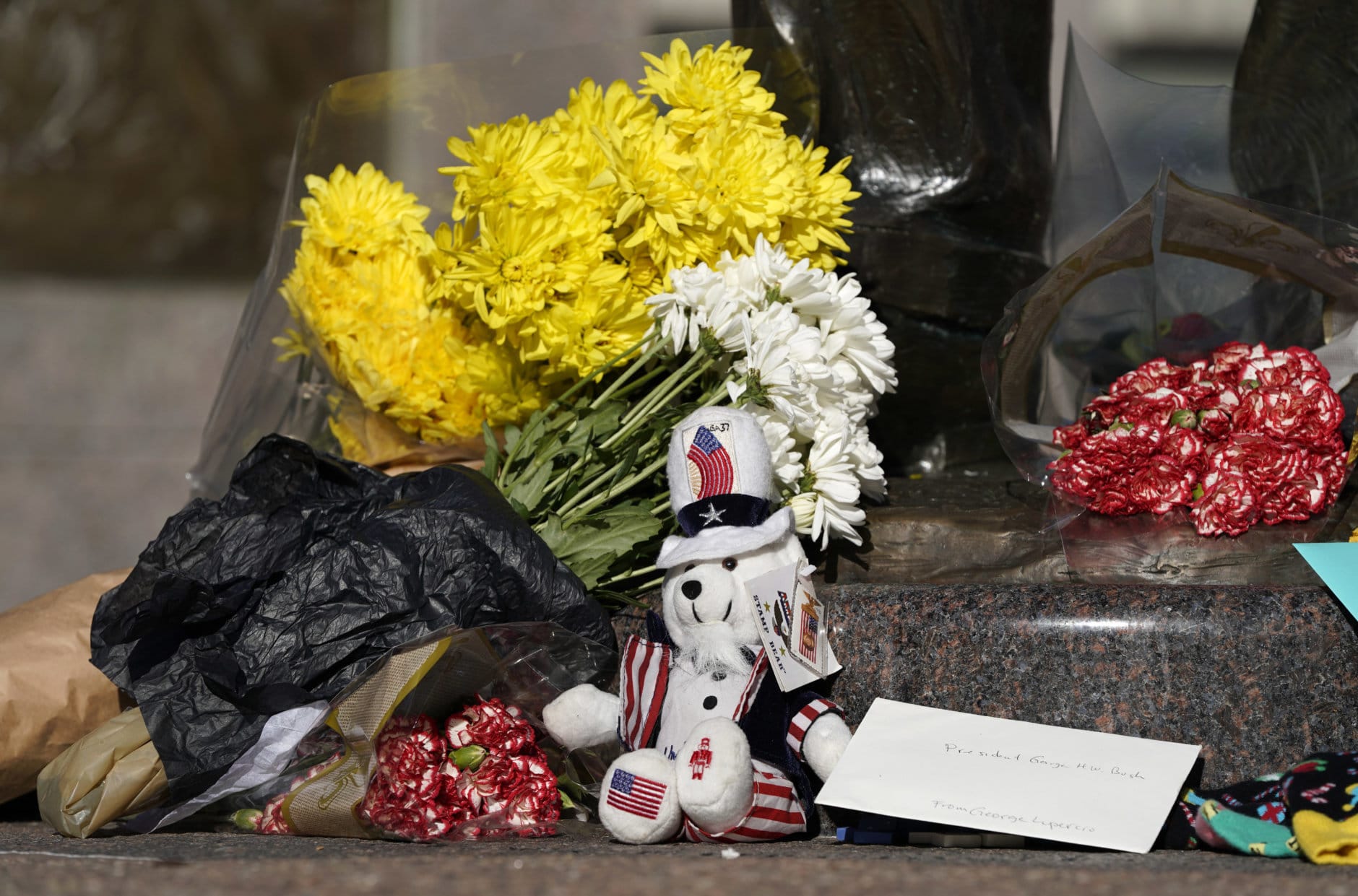 A makeshift memorial is shown at the base of a statue of former President George H.W. Bush in downtown Houston, Sunday, Dec. 2, 2018. Bush is returning to Washington as a revered political statesman, hailed by leaders across the political spectrum and around the world as a man not only of greatness but also of uncommon decency and kindness.  Bush, died late Friday at his Houston home at age 94, is to be honored with a state funeral at National Cathedral in the nation's capital on Wednesday, followed by burial Thursday on the grounds of his presidential library at Texas A&amp;M. (AP Photo/David J. Phillip)