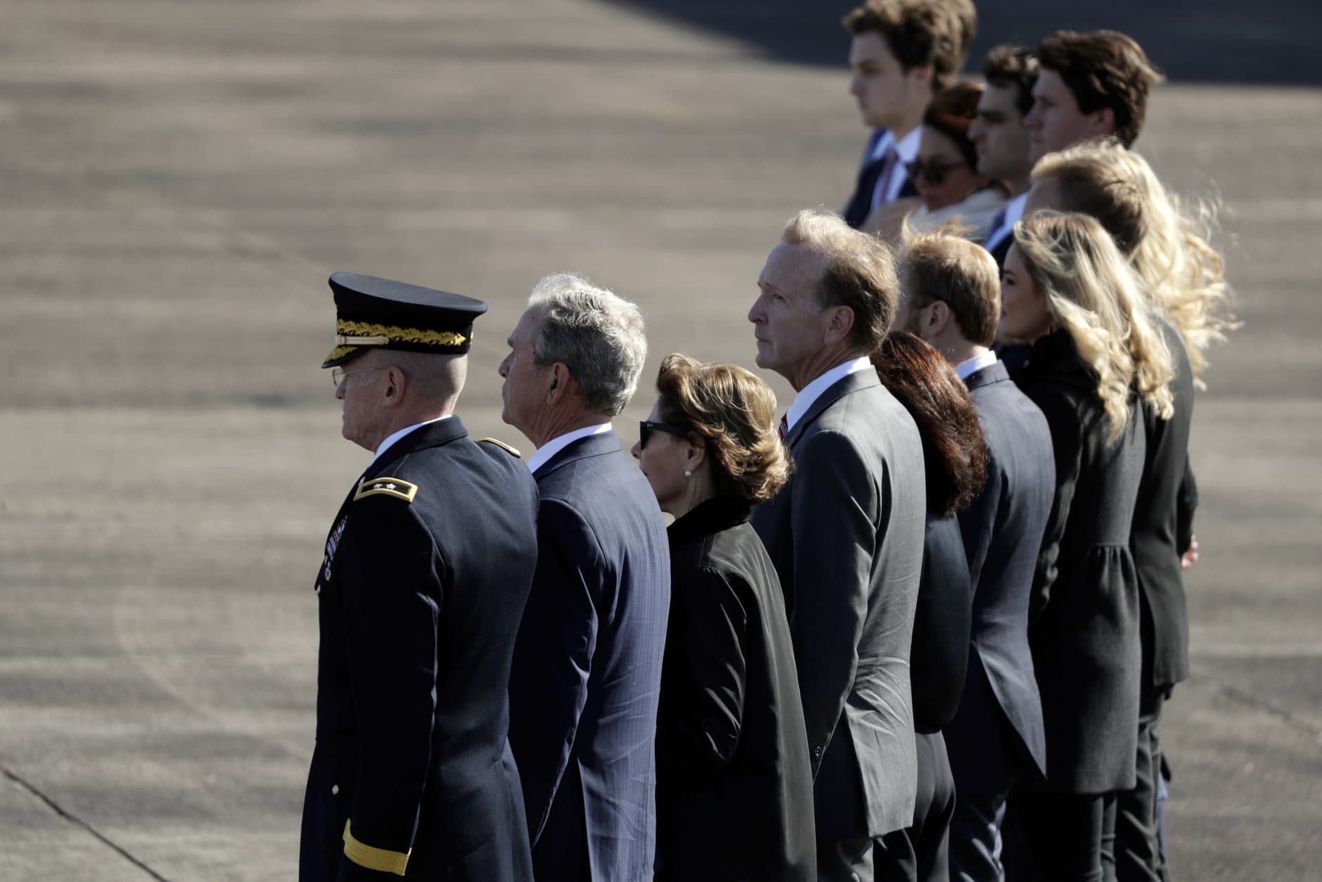Family members of former President George H.W. Bush, including former President George W. Bush, second from left, watch as members of the military carry the casket to Special Air Mission 41at Ellington Field during a departure ceremony for a state funeral, Monday, Dec. 3, 2018, in Houston. (AP Photo/Eric Gay)