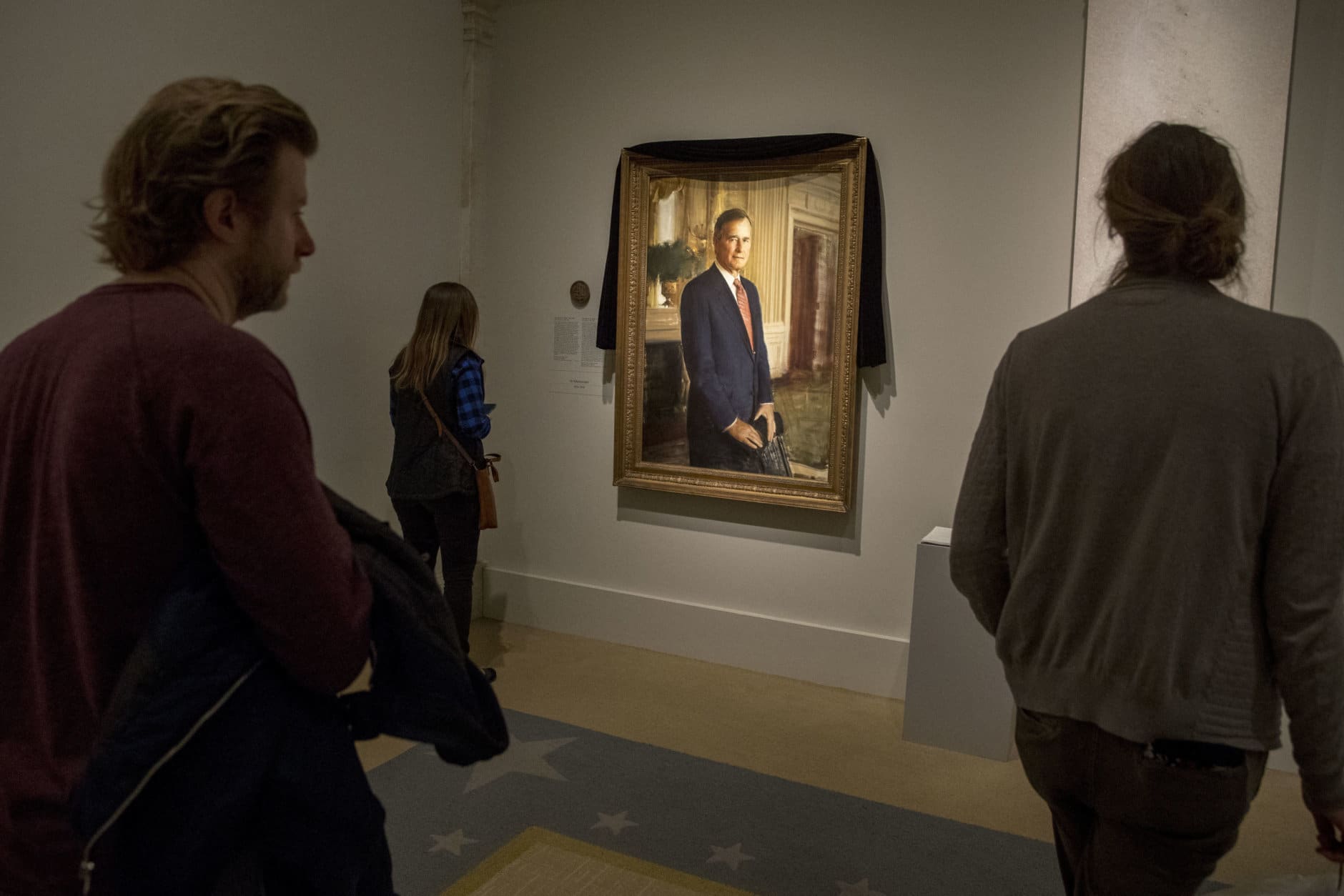 Visitors stop to look at the official portrait of former President George H.W. Bush as it is draped in black cloth at the National Portrait Gallery in Washington, Monday, Dec. 3, 2018, to mark his passing. Bush will lay in state at the Capitol building this week before being buried in Texas. (AP Photo/Andrew Harnik)