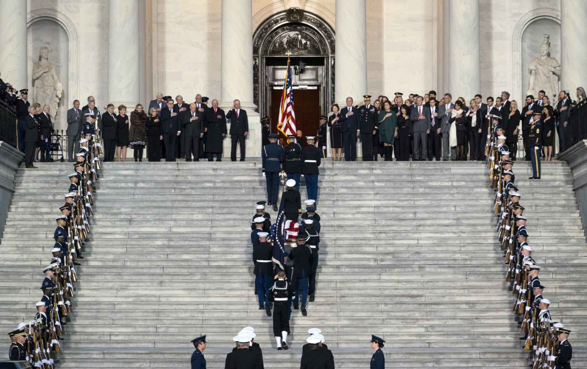 Family members and others watch as the flag-draped of former President George H.W. Bush is carried by a joint services military honor guard to lie in state in the rotunda of the U.S. Capitol, Monday, Dec. 3, 2018, in Washington. (Doug Mills/The New York Times via AP, Pool)