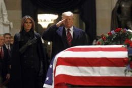 President Donald Trump salutes alongside first lady Melania Trump in front of the flag-draped casket of former President George H.W. Bush in the Capitol Rotunda in Washington, Monday, Dec. 3, 2018. (AP Photo/Patrick Semansky)