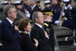President George W. Bush, his wife Laura Bush and brother Jeb Bush watch as the casket of former President George H.W. Bush arrives at the National Cathedral, Wednesday, Dec. 5, 2018, in Washington, for a State Funeral.(AP Photo/Susan Walsh)